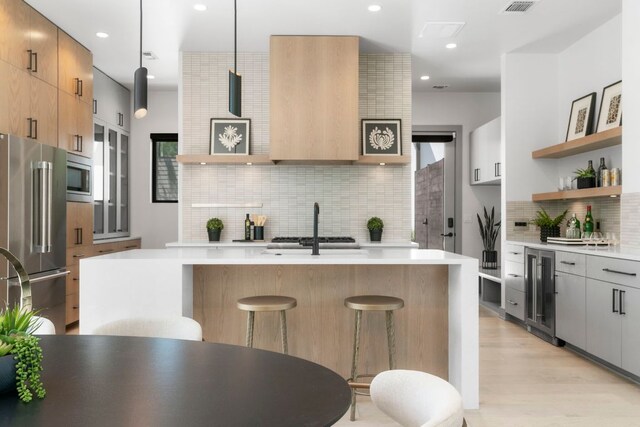 2402 S 3rd St Unit A, Austin, TX 78704 - kitchen featuring stainless steel appliances, decorative backsplash, open shelves, wine cooler, and a breakfast bar area