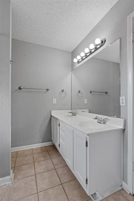 913 Dover Pass, Cedar Park, TX 78613 - bathroom featuring a textured ceiling, double vanity, tile patterned flooring, and baseboards