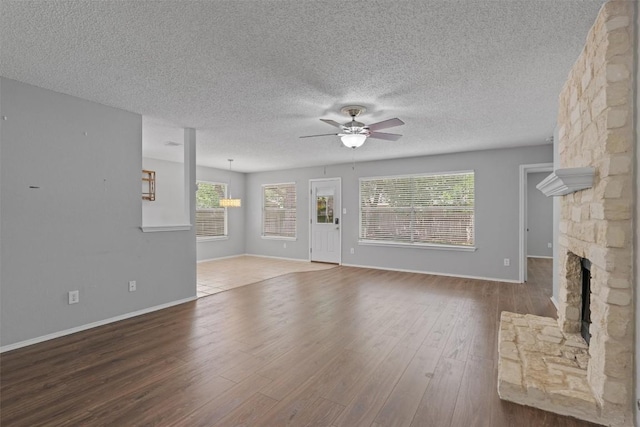 913 Dover Pass, Cedar Park, TX 78613 - unfurnished living room featuring a ceiling fan, a textured ceiling, wood finished floors, baseboards, and a fireplace