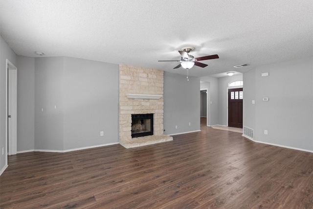913 Dover Pass, Cedar Park, TX 78613 - unfurnished living room featuring ceiling fan, a textured ceiling, dark wood finished floors, baseboards, and a stone fireplace
