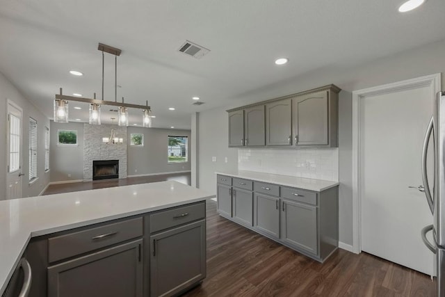 339 Precipice Way, Georgetown, TX 78626 - kitchen featuring gray cabinetry, stainless steel fridge, dark wood-style floors, a fireplace, and decorative backsplash