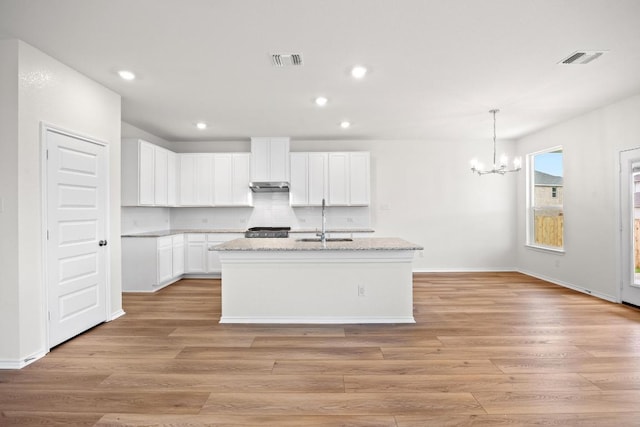 3917 Torraca Ln, Round Rock, TX 78665 - kitchen featuring a chandelier, recessed lighting, light wood finished floors, white cabinetry, and a kitchen island with sink