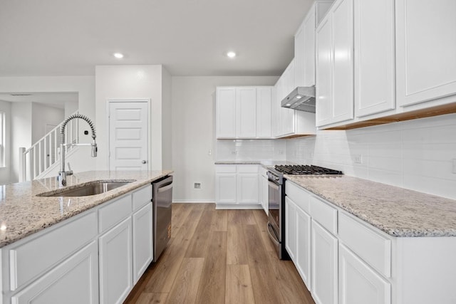 3917 Torraca Ln, Round Rock, TX 78665 - kitchen featuring appliances with stainless steel finishes, under cabinet range hood, light wood finished floors, recessed lighting, and light stone countertops