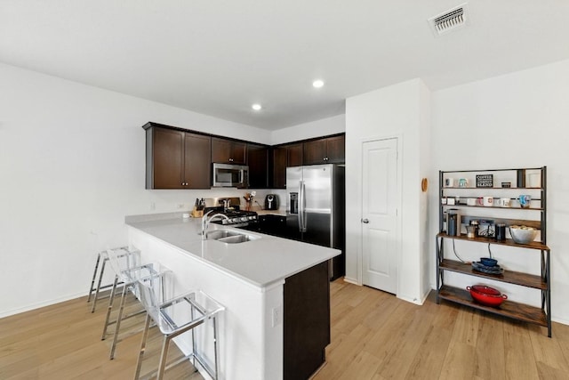 7506 Grenadine Bloom Bnd, Del Valle, TX 78617 - kitchen featuring stainless steel appliances, light wood-style flooring, dark brown cabinetry, light countertops, and recessed lighting