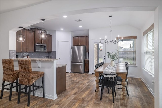 309 Callahan Ln, Leander, TX 78641 - kitchen with stainless steel appliances, tasteful backsplash, a peninsula, a breakfast bar, and dark wood finished floors