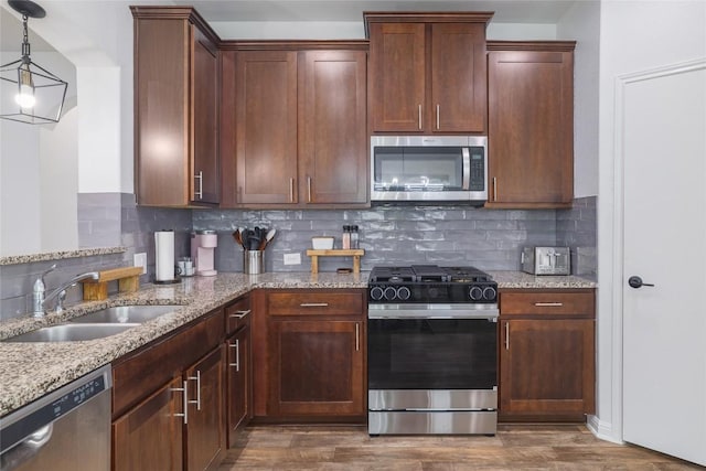 309 Callahan Ln, Leander, TX 78641 - kitchen featuring appliances with stainless steel finishes, a sink, dark wood-style flooring, and light stone countertops