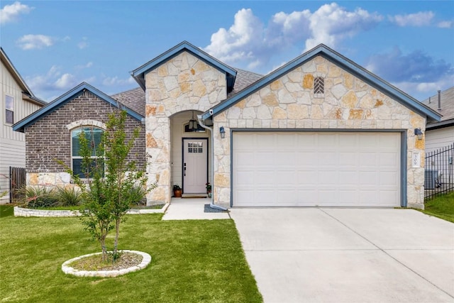 309 Callahan Ln, Leander, TX 78641 - french provincial home with stone siding, a front yard, a garage, driveway, and roof with shingles