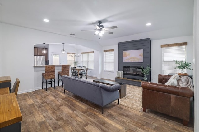 309 Callahan Ln, Leander, TX 78641 - living room with arched walkways, ceiling fan, dark wood-type flooring, baseboards, and a large fireplace