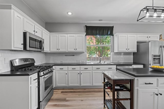 120 Spring Ct, Georgetown, TX 78633 - kitchen with appliances with stainless steel finishes, a sink, dark countertops, white cabinetry, and recessed lighting