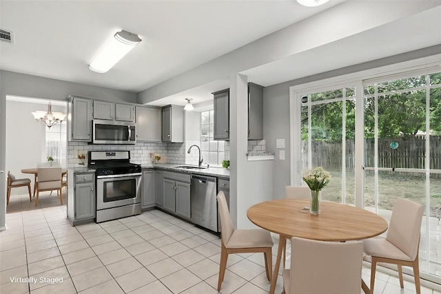 902 Valley Glen Cv, Pflugerville, TX 78660 - kitchen featuring gray cabinets, appliances with stainless steel finishes, a sink, tasteful backsplash, and light tile patterned floors
