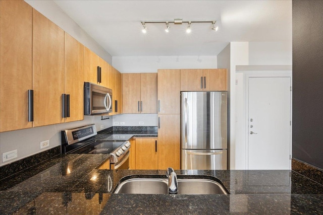 54 Rainey St Unit 815, Austin, TX 78701 - kitchen with appliances with stainless steel finishes, dark stone countertops, a sink, and track lighting