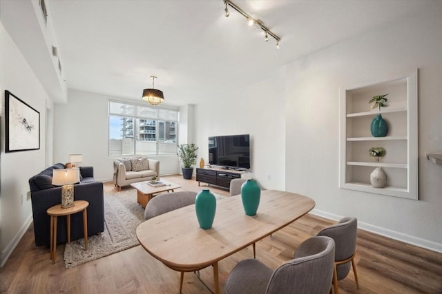 54 Rainey St Unit 815, Austin, TX 78701 - living area featuring wood finished floors, rail lighting, baseboards, and built in features