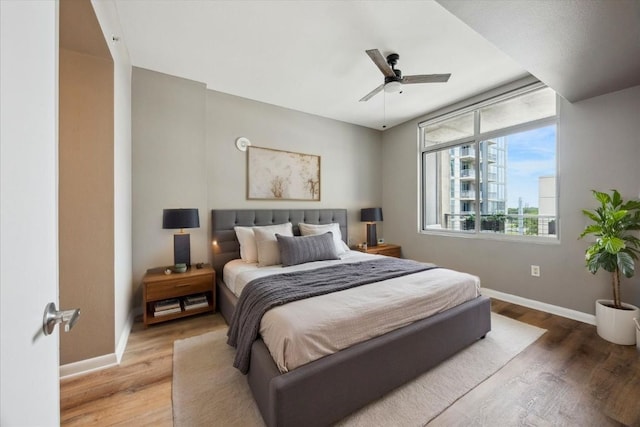 54 Rainey St Unit 815, Austin, TX 78701 - bedroom with baseboards, wood finished floors, and a ceiling fan
