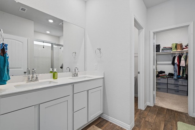 204 Connor Ln, Georgetown, TX 78626 - bathroom with a stall shower, double vanity, a walk in closet, wood finished floors, and baseboards
