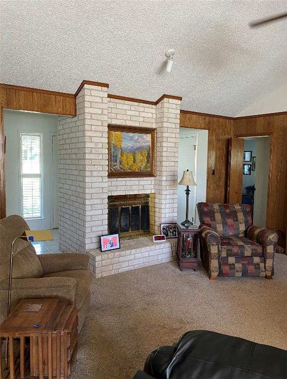 4105 Val Verde Dr, Georgetown, TX 78628 - carpeted living area with a textured ceiling, wooden walls, and a brick fireplace