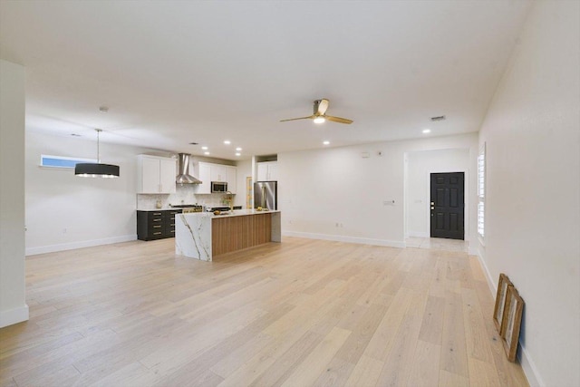 515 Mill Pond Path, Georgetown, TX 78633 - kitchen featuring appliances with stainless steel finishes, wall chimney range hood, open floor plan, ceiling fan, and a center island with sink