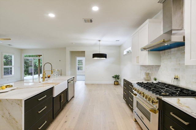 515 Mill Pond Path, Georgetown, TX 78633 - kitchen featuring appliances with stainless steel finishes, wall chimney exhaust hood, a sink, white cabinetry, and baseboards
