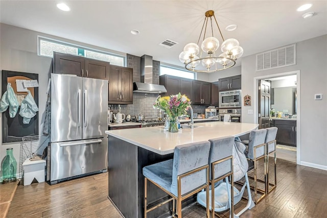 1142 Lost Creek Blvd Unit 12, Austin, TX 78746 - kitchen featuring appliances with stainless steel finishes, wall chimney range hood, tasteful backsplash, light countertops, and a breakfast bar