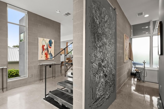 1003 E 8th St, Austin, TX 78702 - staircase featuring finished concrete flooring, tile walls, healthy amount of natural light, concrete block wall, and recessed lighting