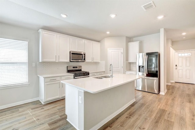 2824 Smokehouse Trl, Round Rock, TX 78665 - kitchen with stainless steel appliances, a sink, light wood-style floors, white cabinets, and a kitchen island with sink
