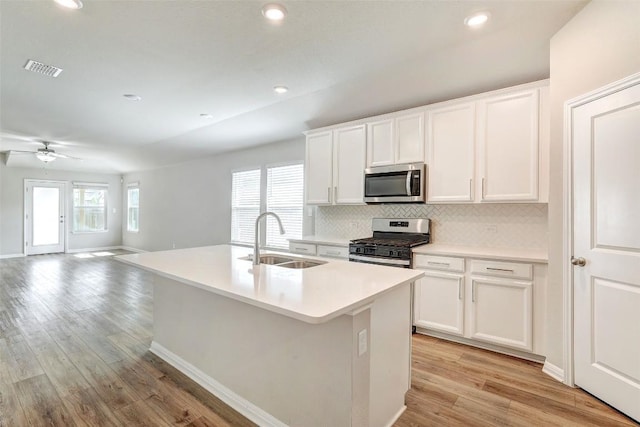 2824 Smokehouse Trl, Round Rock, TX 78665 - kitchen with stainless steel appliances, decorative backsplash, a center island with sink, light wood-type flooring, and white cabinetry