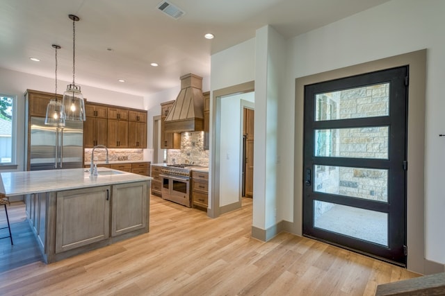 208 E Lakeshore Dr, Sunrise Beach, TX 78643 - kitchen featuring high quality appliances, a sink, premium range hood, tasteful backsplash, and hanging light fixtures