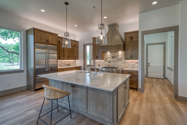208 E Lakeshore Dr, Sunrise Beach, TX 78643 - kitchen with stainless steel built in refrigerator, light stone counters, backsplash, a sink, and custom range hood