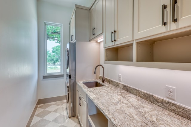 208 E Lakeshore Dr, Sunrise Beach, TX 78643 - kitchen featuring a sink, light flooring, light stone counters, baseboards, and open shelves