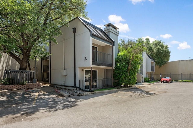935 La Posada Dr Unit 243, Austin, TX 78752 - view of front of property with uncovered parking, a chimney, metal roof, and a standing seam roof