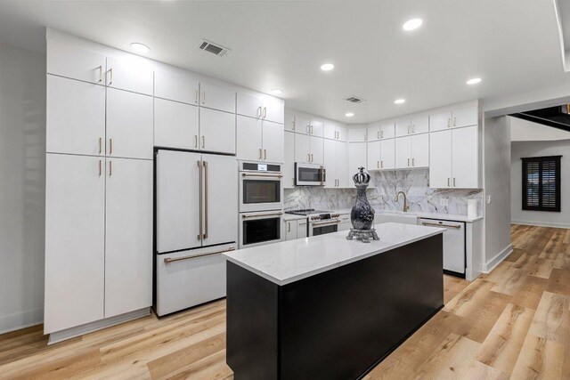 129 Cedar Dr, Horseshoe Bay, TX 78657 - kitchen featuring stainless steel appliances, white cabinets, a sink, decorative backsplash, and a center island