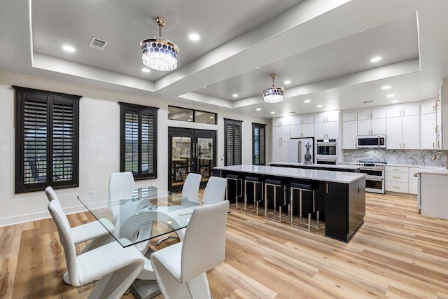129 Cedar Dr, Horseshoe Bay, TX 78657 - dining area with a tray ceiling, light wood finished floors, recessed lighting, a chandelier, and french doors
