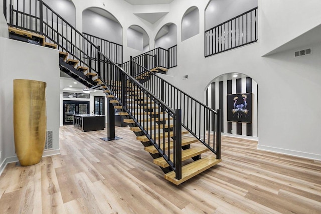 129 Cedar Dr, Horseshoe Bay, TX 78657 - staircase featuring a towering ceiling, arched walkways, wood finished floors, and baseboards
