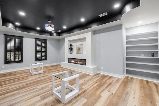 129 Cedar Dr, Horseshoe Bay, TX 78657 - unfurnished living room featuring baseboards, wood finished floors, a glass covered fireplace, a raised ceiling, and recessed lighting