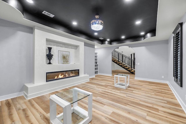 129 Cedar Dr, Horseshoe Bay, TX 78657 - living room with arched walkways, a glass covered fireplace, baseboards, stairway, and recessed lighting