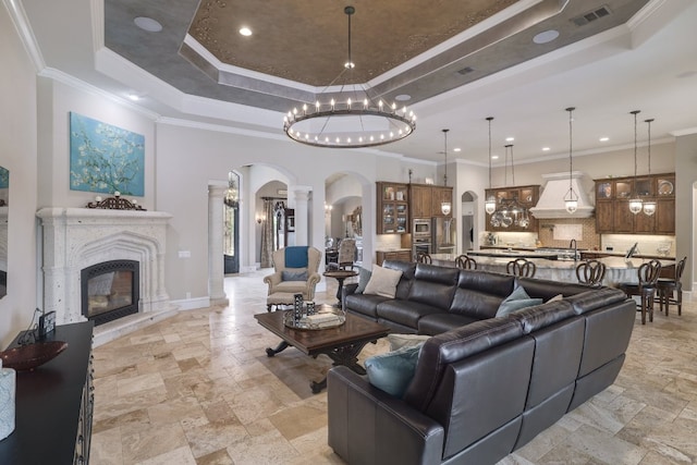 700 Zen Gardens Ter, Austin, TX 78732 - living room with arched walkways, a tray ceiling, stone tile flooring, ornate columns, and recessed lighting