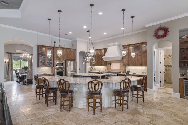 700 Zen Gardens Ter, Austin, TX 78732 - kitchen with arched walkways, premium range hood, stainless steel appliances, a large island with sink, and tasteful backsplash