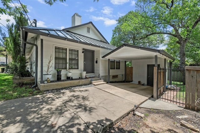 2814 Windsor Rd, Austin, TX 78703 - view of front facade featuring a standing seam roof, concrete driveway, a carport, a chimney, and metal roof
