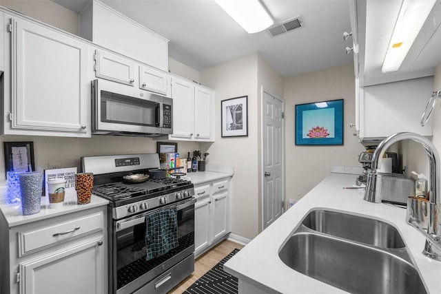 2814 Windsor Rd, Austin, TX 78703 - kitchen featuring appliances with stainless steel finishes, a sink, light countertops, and white cabinetry
