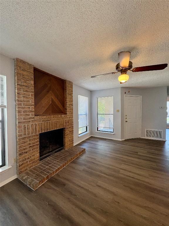 10616 Mellow Meadows Dr Unit 35C, Austin, TX 78750 - unfurnished living room with wood finished floors, a textured ceiling, a fireplace, baseboards, and a ceiling fan