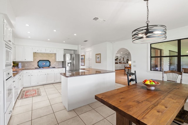 618 Hi Stirrup, Horseshoe Bay, TX 78657 - kitchen featuring white appliances, arched walkways, light tile patterned flooring, a kitchen island, and recessed lighting