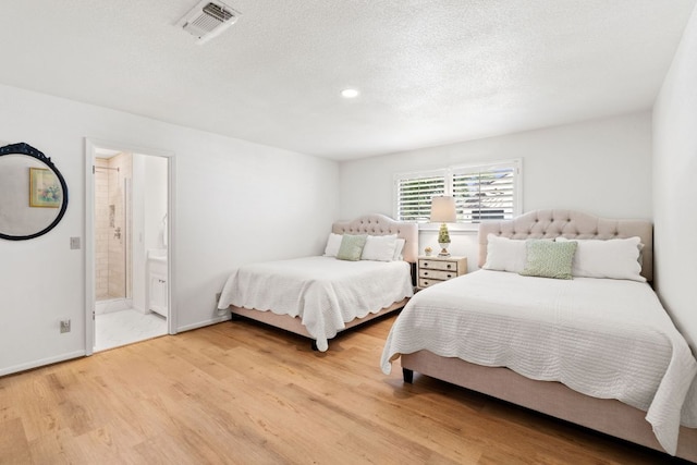 618 Hi Stirrup, Horseshoe Bay, TX 78657 - bedroom with light wood-style floors, connected bathroom, recessed lighting, a textured ceiling, and baseboards