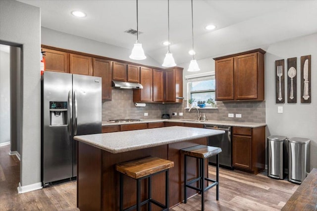2313 Jake Pickle Pass, Leander, TX 78641 - kitchen featuring appliances with stainless steel finishes, under cabinet range hood, wood finished floors, decorative backsplash, and recessed lighting