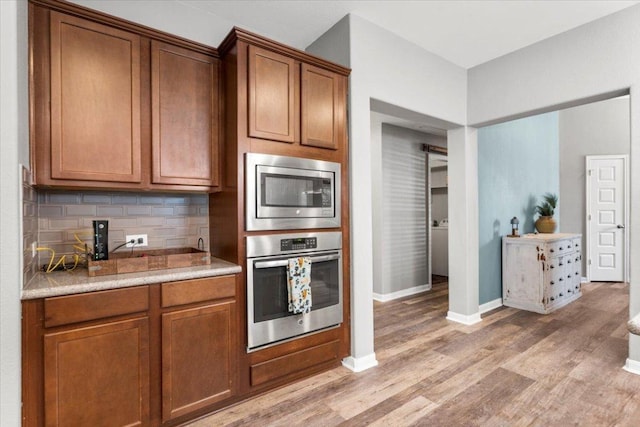 2313 Jake Pickle Pass, Leander, TX 78641 - kitchen with appliances with stainless steel finishes, light wood-style floors, backsplash, light countertops, and brown cabinets