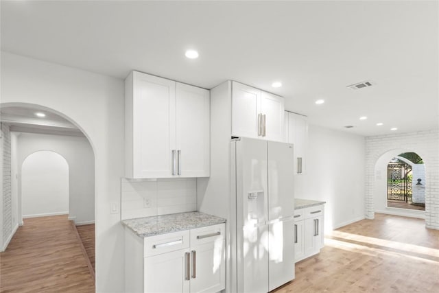 4202 N Hills Dr, Austin, TX 78731 - kitchen featuring white fridge with ice dispenser, arched walkways, light wood-style flooring, light stone countertops, and recessed lighting