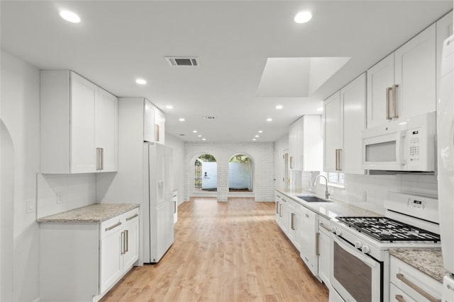 4202 N Hills Dr, Austin, TX 78731 - kitchen with white appliances, arched walkways, white cabinets, recessed lighting, and decorative backsplash