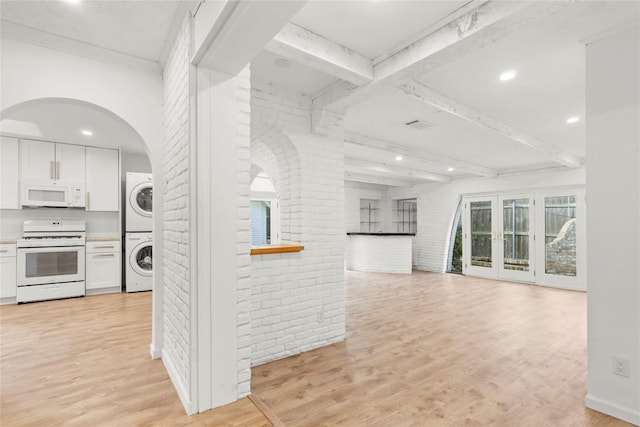 4202 N Hills Dr, Austin, TX 78731 - kitchen with white appliances, stacked washer / dryer, brick wall, white cabinetry, and light wood-type flooring