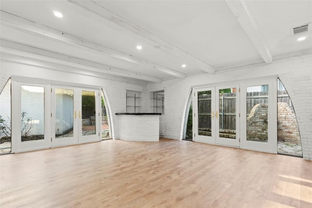 4202 N Hills Dr, Austin, TX 78731 - unfurnished living room featuring french doors, healthy amount of natural light, brick wall, beamed ceiling, and wood finished floors