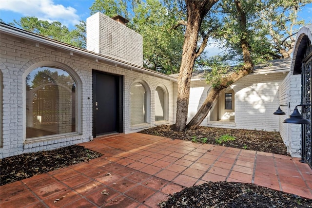 4202 N Hills Dr, Austin, TX 78731 - property entrance featuring a chimney, brick siding, and a patio