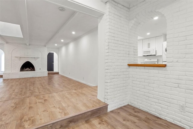 4202 N Hills Dr, Austin, TX 78731 - unfurnished living room with brick wall, light wood-style flooring, recessed lighting, arched walkways, and beam ceiling