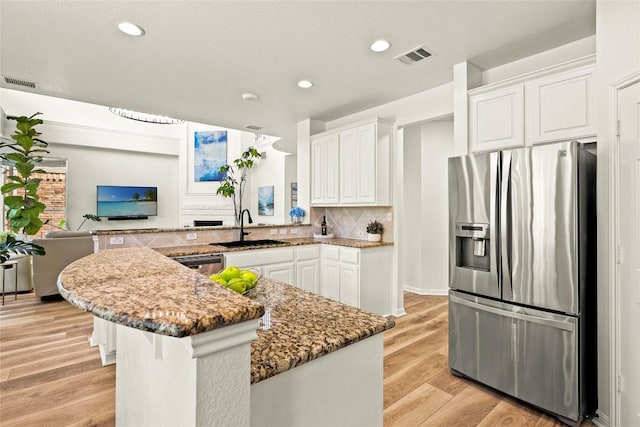 220 Grafton Ln, Austin, TX 78737 - kitchen with appliances with stainless steel finishes, a sink, white cabinets, dark stone counters, and a peninsula
